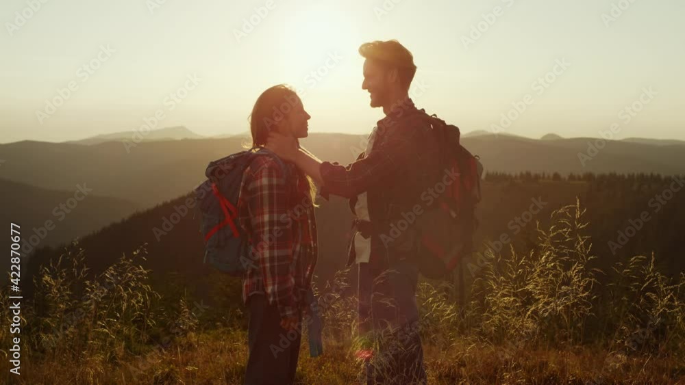 Loving girl and guy spending time together in mountains at sunset Loving girl and guy spending time together in mountains at sunset
