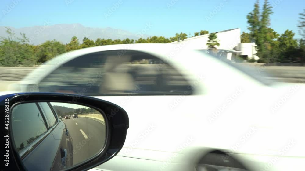 View from rear mirror of car driving fast on sunny day on freeway. Day trip concept View from rear mirror of car driving fast on sunny day on freeway. Day trip concept