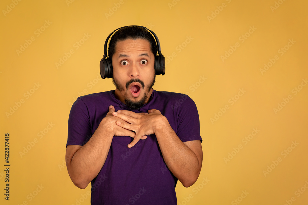 Obraz premium Portrait of man with funny face using headphone with yellow background. Man with surprised face.