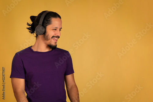 Portrait of man using headphone with yellow background