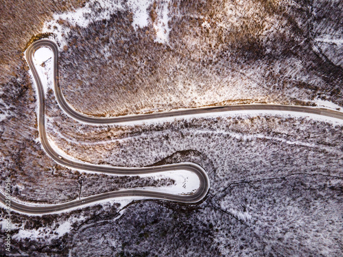 High angle aerial view drone image on the curved serpentine road trough the trees and forest in mountain range with white snow in winter day near Knjazevac in Serbia - Travel journey vacation concept photo