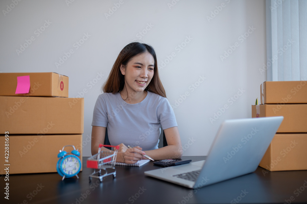 Small business entrepreneur SME freelance,Portrait young woman working on laptop at home office, online marketing packaging delivery box, SME e-commerce concept Small business entrepreneur SME freelance,Portrait young woman working on laptop at home office, online marketing packaging delivery box, SME e-commerce concept