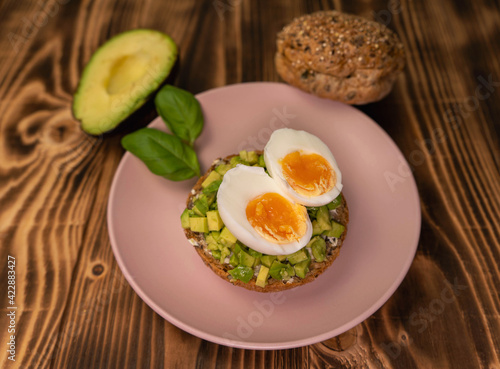 Healthy vegetarian food breakfast meal, sandwich made from avocado cubes with sunflower oil, soft cheese, cucumber and boiled egg on whole grain buns. Wooden board, close up