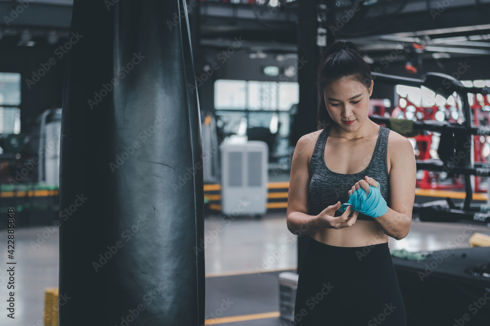Portrait beauty sport woman wear sportwear ,boxing glove posing in boxing area under exercise with fitness equipment at gym ,she exercise for strong ,make muscle and good healthy.
