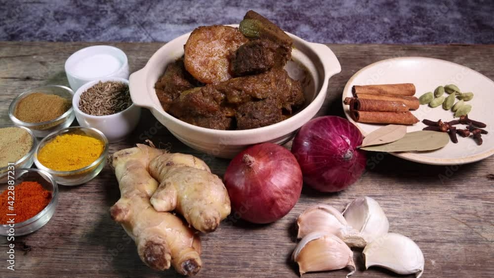 Beef bhuna dry curry with potato in ceramic bowl ingredients chilli cumin coriander turmeric powered salt onion garlic ginger bay leaf cinnamon cardamom clove over rustic wood background Beef bhuna dry curry with potato in ceramic bowl ingredients chilli cumin coriander turmeric powered salt onion garlic ginger bay leaf cinnamon cardamom clove over rustic wood background