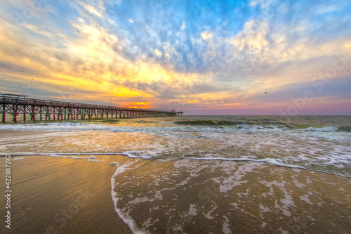 Dramatic sunrise beach with fishing pier in Myrtle Beach, South Carolina.