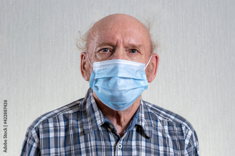 Old bald man in mask. Indoors in daylight. Front view. Old bald man in mask. Indoors in daylight. Front view.