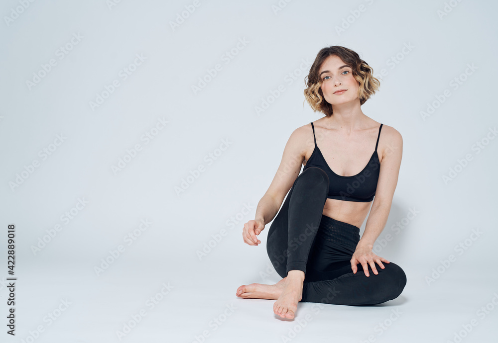 Woman in sportswear sits on the floor in a bright room and t-shirt leggings