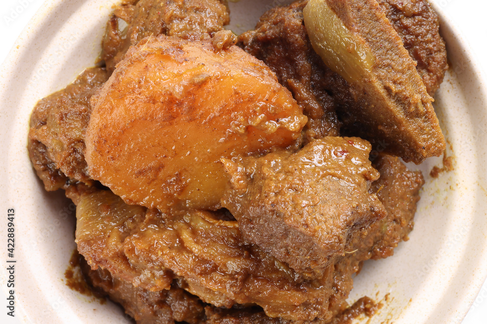 Asian style Beef bhuna dry curry with potato in ceramic bowl over white