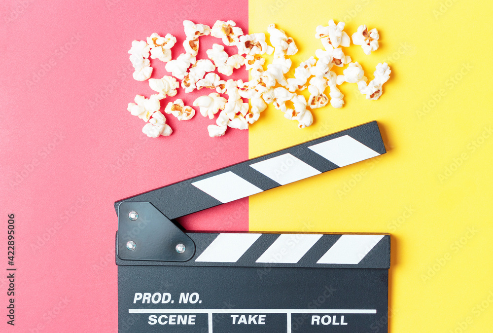 The clapperboard and popcorn on yellow and red background top view.