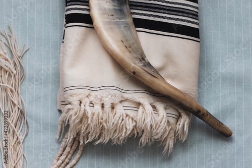 A close-up photo of a shofar and tallit, on a light background photo