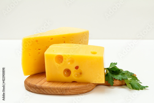 Cheese and parsley on wooden cutting board on white background