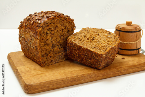 Cut loaf of bread on wooden cutting board on white background