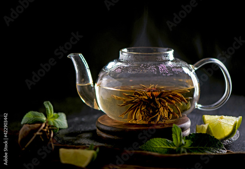 Tea concept, teapot with tea surrounded on wood background, tea ceremony, green tea in a transparent cup