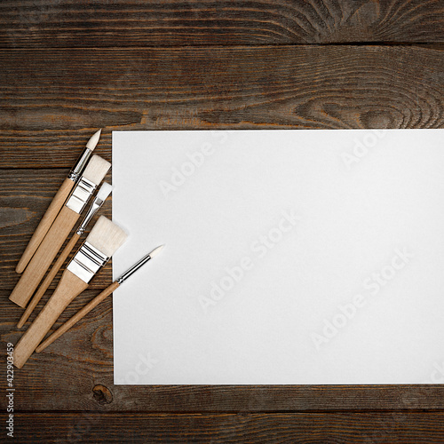 A clean white sheet and brushes on a wood textured background with space to copy.