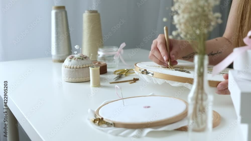 Young girl sits on workspace in light workshop and embroiders with beads. designer makes handmade jewelry. Hobby concept. Self-employed freelancer makes creativity Young girl sits on workspace in light workshop and embroiders with beads. designer makes handmade jewelry. Hobby concept. Self-employed freelancer makes creativity