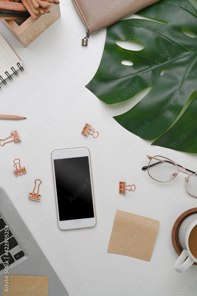 Above view of white office desk with mobile phone, glasses, coffee cup and stationery. Above view of white office desk with mobile phone, glasses, coffee cup and stationery.
