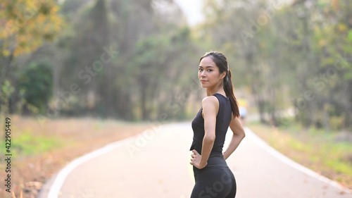 Healthy young woman in sportswear standing in the park and looking at camera.