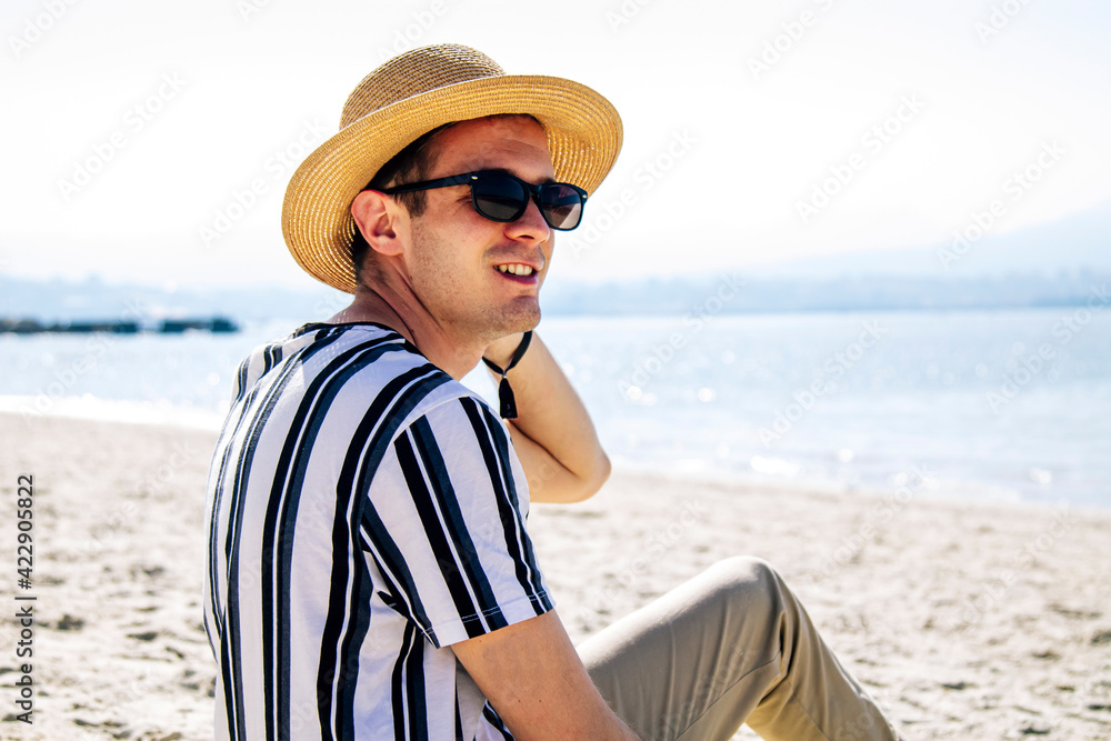 relaxed man sitting on the sand on the beach looking at the sea