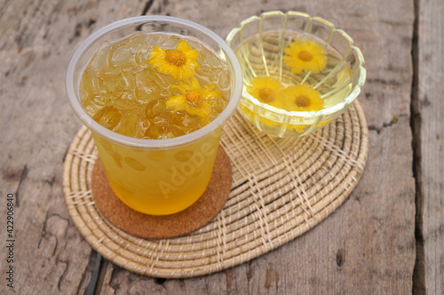 Chrysanthemum juice in a glass placed on a wooden table.