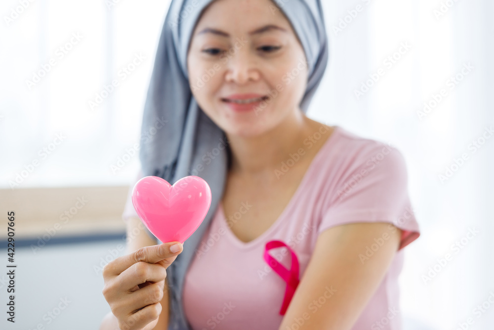 close up of women cancer patient with pink ribbon wearing headscarf After treatment to chemotherapy with holding small a pink hearts shaped at home,medicine concept close up of women cancer patient with pink ribbon wearing headscarf After treatment to chemotherapy with holding small a pink hearts shaped at home,medicine concept
