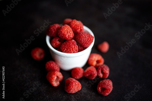 Organic Red raspberry in a bowl, isolated on a black background. Close-up of fresh Red raspberry fruits. Ripe berries bowl. Summer sweet fruits.