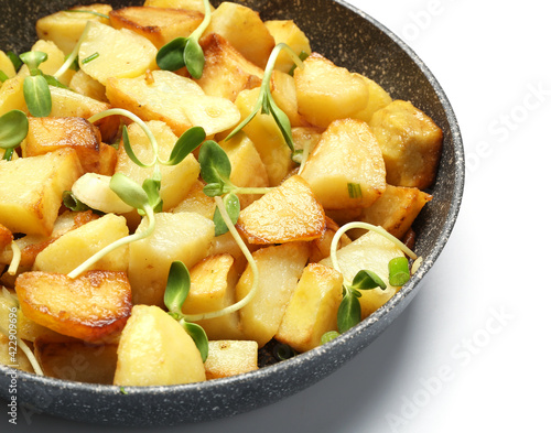Frying pan with tasty potato on white background, closeup