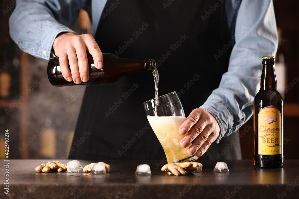 Bartender pouring fresh ginger beer into glass on table in bar Bartender pouring fresh ginger beer into glass on table in bar