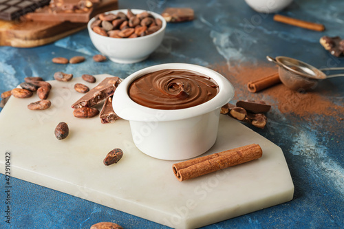 Bowl of tasty melted chocolate on color background