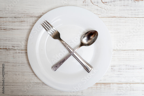 The spoon and fork are on an empty plate. Diet concept, intermittent fasting. photo