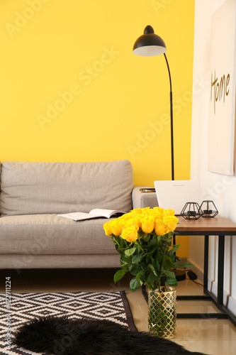 Vase with beautiful yellow roses in interior of room
