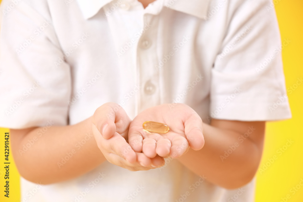 Little boy with fish oil on color background, closeup Little boy with fish oil on color background, closeup