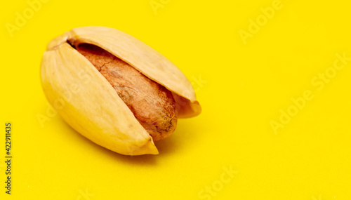 Close-up of fresh pistachio nuts on a yellow background.