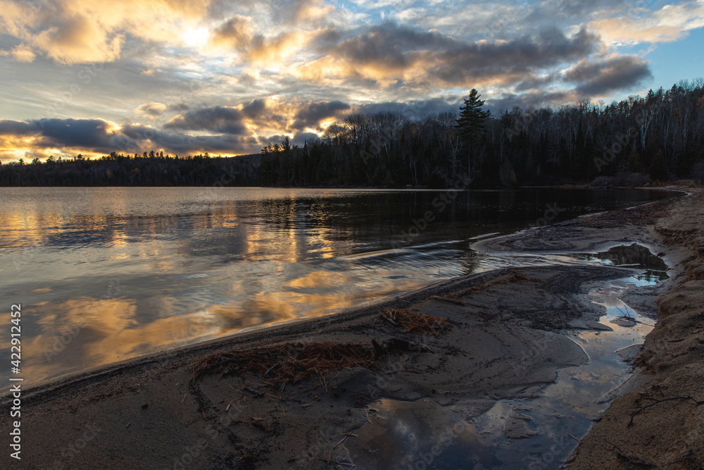 Fin d'un coucher de soleil avec lumière jaune sur un lac avec effet miroir sur la surface vue de la plage