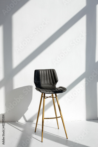 Empty modern chair in room  stine sunlight  white walls. Minimalistic interior  concept of cleanliness  loneliness  calm  cleansing  copy space  stylish trendy studio mock up