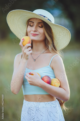 Young beautiful girl with peaches in hands in nature