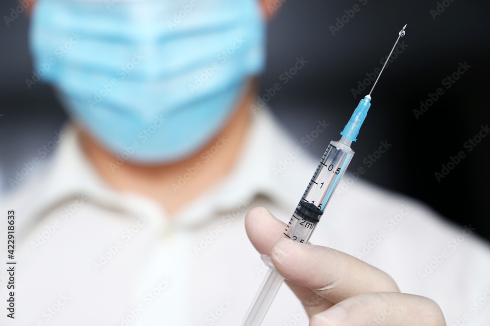 Doctor with syringe in hand, man in medical mask and protective gloves preparing to injection. Concept of vaccination during covid-19 pandemic Doctor with syringe in hand, man in medical mask and protective gloves preparing to injection. Concept of vaccination during covid-19 pandemic