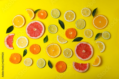 Ripe citrus slices and leaves on yellow background