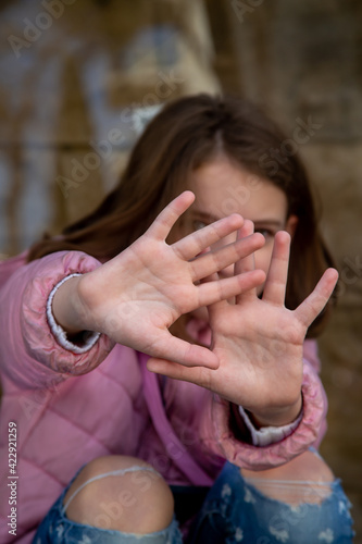 a teenage girl in a pink jacket is in a public place and has her arms outstretched in defense