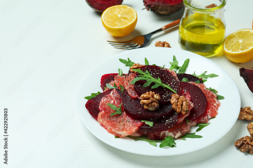 Plate of tasty beet salad and ingredients on white background Plate of tasty beet salad and ingredients on white background
