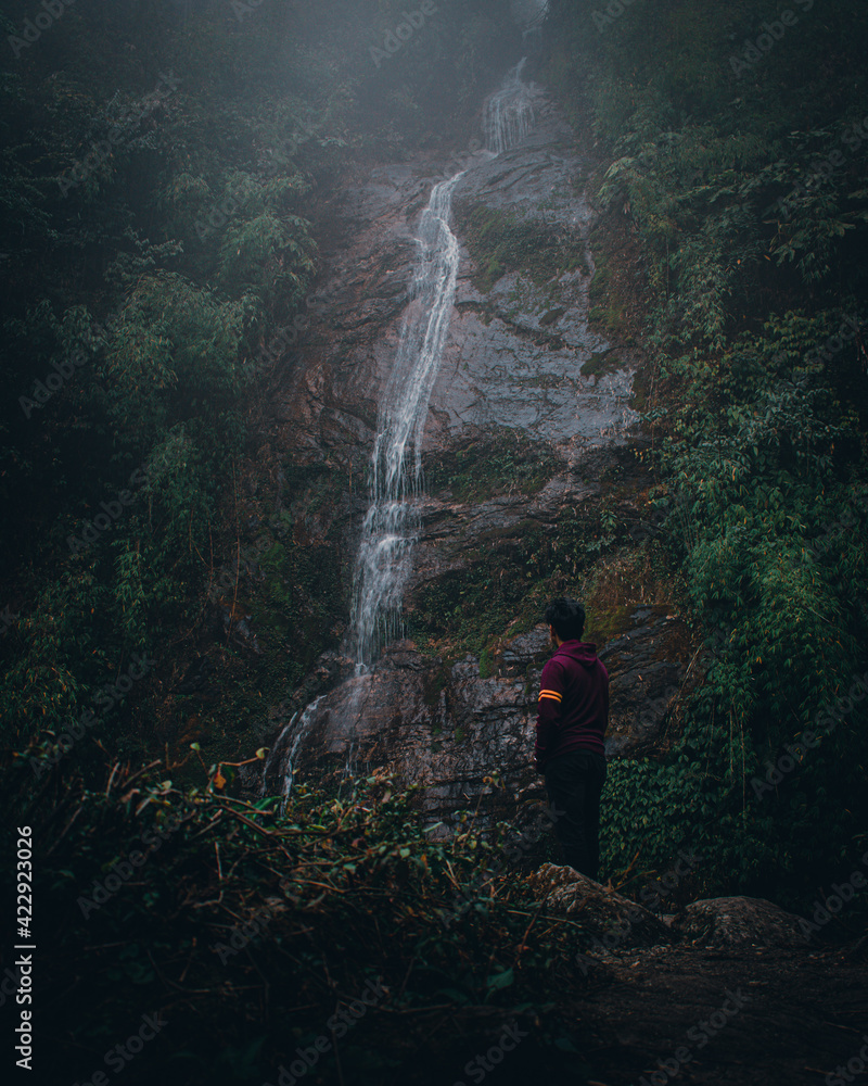 person walking near a mountain waterfall person walking near a mountain waterfall