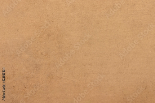 The surface of old worn brown cardboard, covered with creases and stains. Uniform light abstract texture.