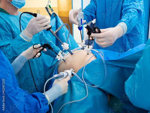 Tableau sur toile Surgeons wearing latex gloves and blue uniforms perform laparoscopic minimally invasive surgery using special medical instruments