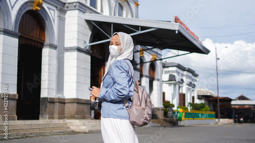 Asian women traveling by train in front of the station wearing jilbab and analog camera © HumbaFrame