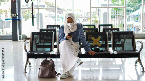 Asian women are tired of waiting at the station wearing jilbab and analog camera