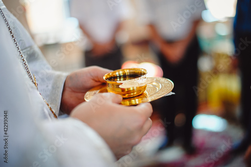 Holy Communion in the hands of the priest. Gold cup with communions. Selective focus photo