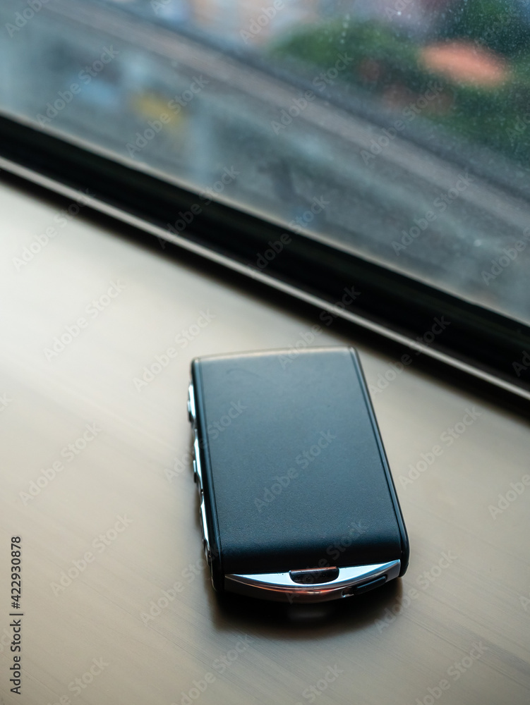 Black key fob remote control on window with natural light Black key fob remote control on window with natural light
