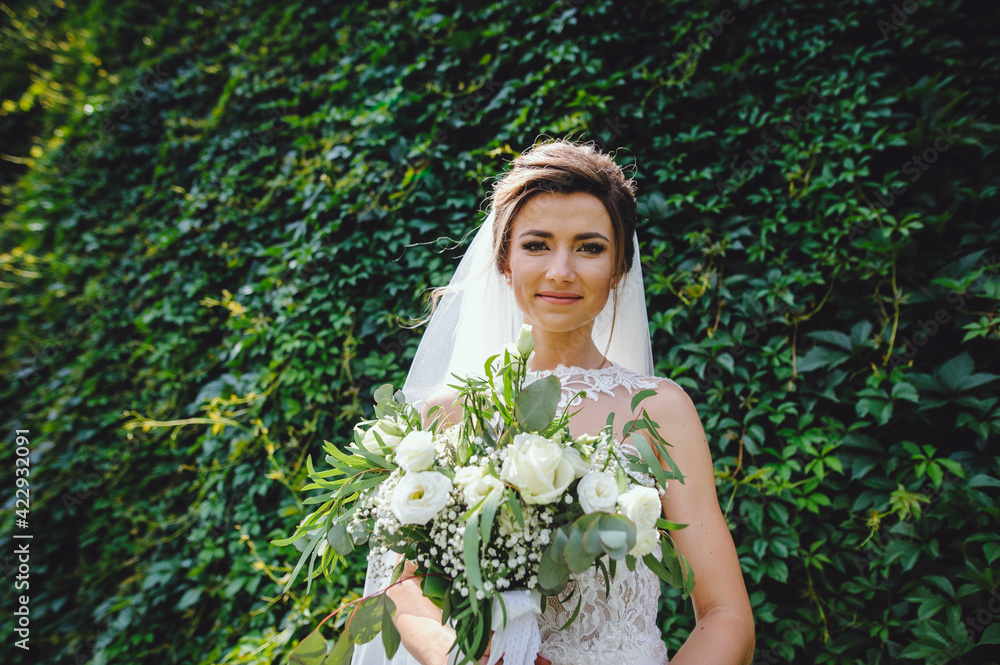 Portrait of a beautiful bride smiling and holding a big wedding bouquet of white flowers and greens. Happy bride on her wedding day. Bride morning. Portrait of a beautiful bride smiling and holding a big wedding bouquet of white flowers and greens. Happy bride on her wedding day. Bride morning.