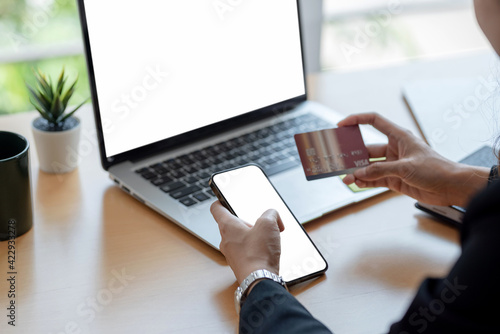 Image woman hand holding credit card shopping online using a smartphone blank white screen at the office. Mock up.