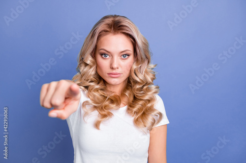 Photo of young pretty charming unhappy upset sad girl pointing finger at camera blaming isolated on blue color background